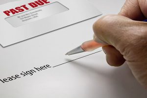 Pen in hand ready to sign a signature regarding a debt